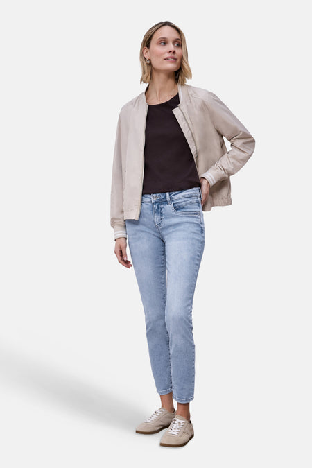 Jean slim en denim bleu clair de Street One, porté avec un t-shirt marron et une veste beige.