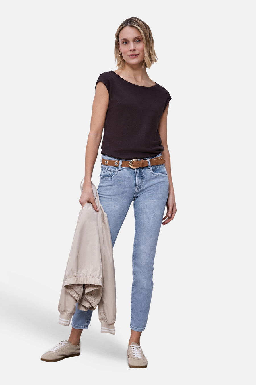 Jean slim en denim bleu clair de STREET ONE, porté avec une ceinture marron et une veste beige.