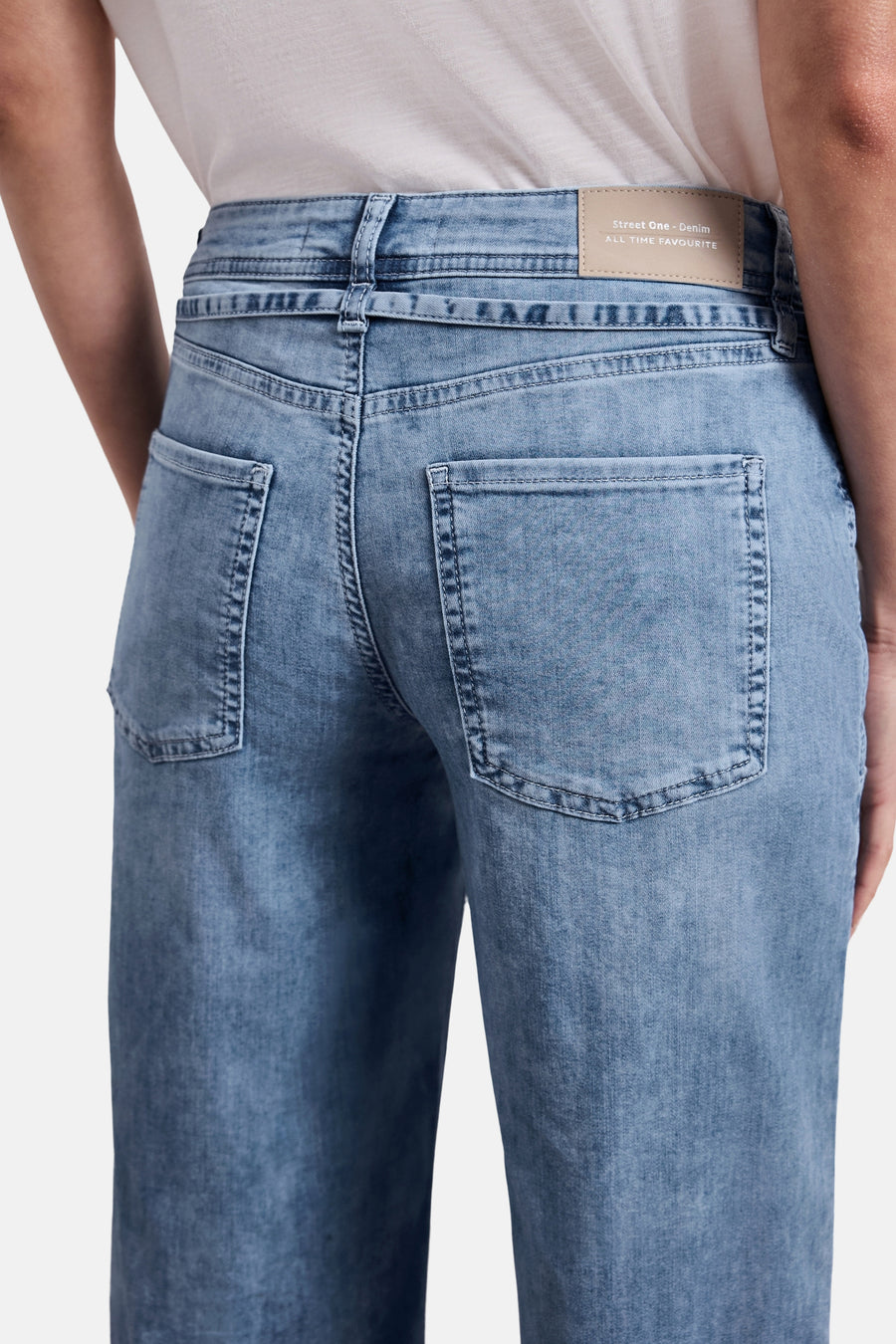 Wijde spijkerbroek in middieblauw denim van Street One, achterkant met beige merklabel, grote zakken en naden.