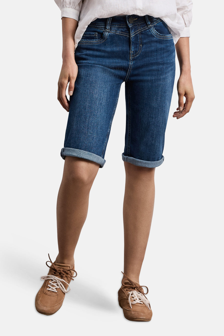 Bermuda en denim bleu moyen de STREET ONE avec ourlet retroussé, porté avec une blouse blanche et des baskets marron.