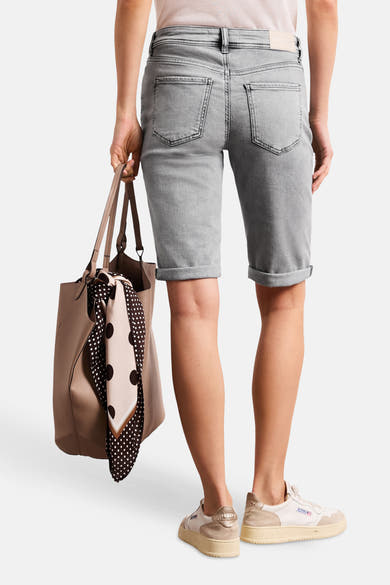Bermuda en jean gris moyen de STREET ONE, avec poches arrière, ourlets retroussés, porté de dos avec sac beige et baskets claires.