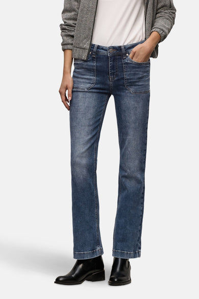 Jean bootcut en denim bleu moyen de Street One, porté avec des bottines noires et un blouson chiné.
