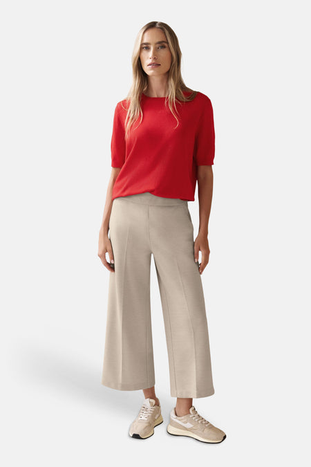 Pantalon de costume beige par Street One, ample avec des plis, porté avec un haut rouge et des baskets.