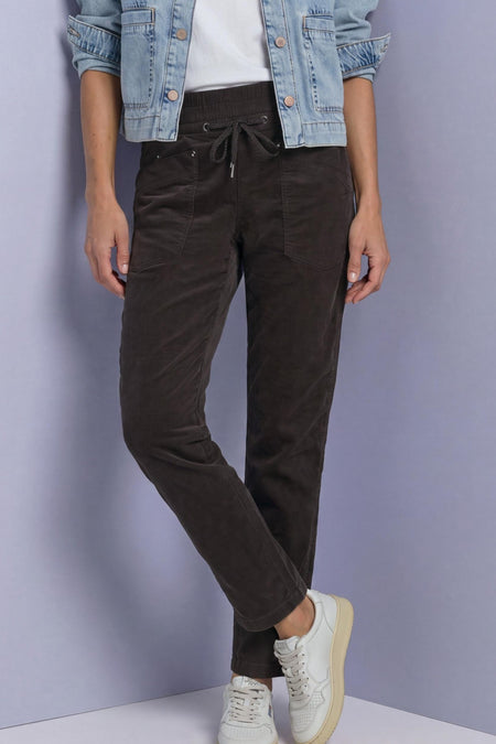 Brown corduroy pants with elastic waist and drawstring by STREET ONE, featuring front pockets, worn with a denim jacket and white sneakers in a lifestyle pose.
