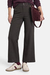 Pantalon de costume brun à fines rayures verticales, porté avec un pull et des baskets