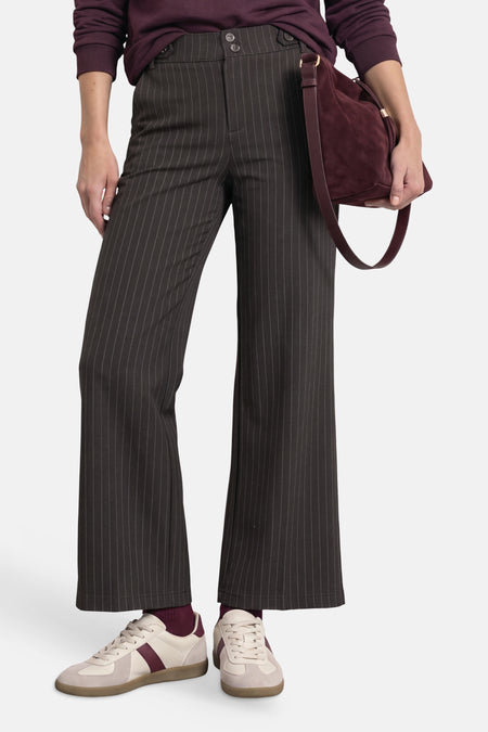 Pantalon de costume brun à fines rayures verticales, porté avec un pull et des baskets