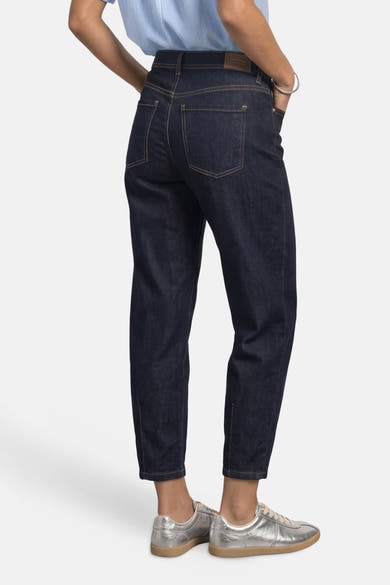 Dark blue denim jeans by STREET ONE, back view with slim tapered fit, visible stitching, and silver sneakers.