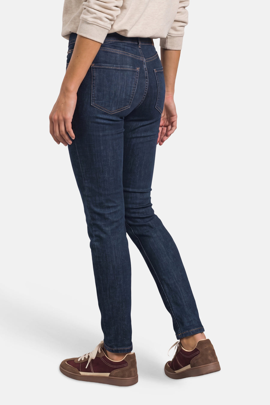 Dark blue slim-fit denim jeans by STREET ONE, back view showing clean stitching and classic five-pocket design, worn with beige sweater and brown sneakers.