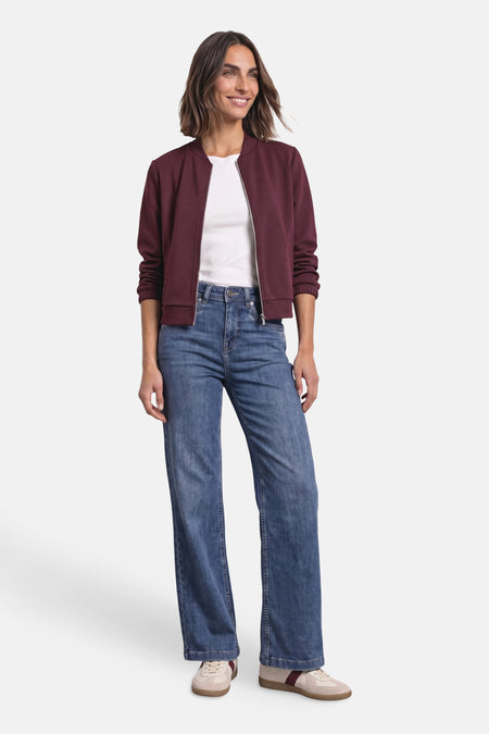 Jean large bleu denim STREET ONE porté par un mannequin, avec veste bordeaux et baskets.