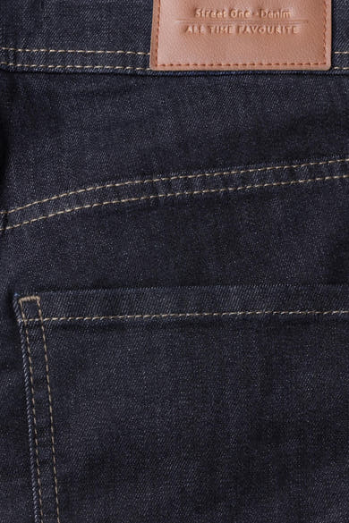 Gros plan sur un jean bootcut en denim bleu foncé STREET ONE, avec surpiqûres contrastantes et étiquette en cuir.
