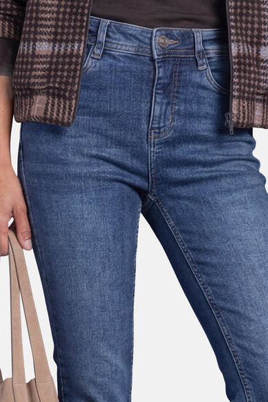 Gros plan sur un jean bootcut bleu denim STREET ONE porté, avec fermeture à bouton, poches et surpiqûres contrastées.
