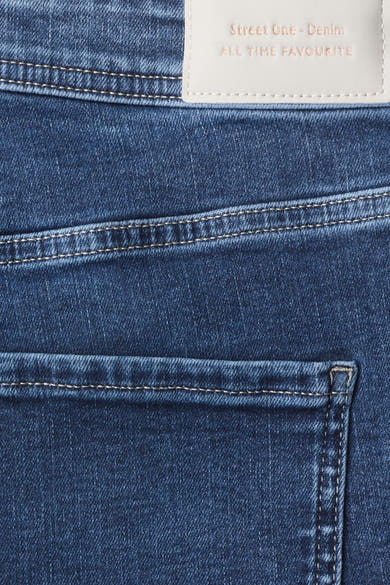 Gros plan sur le denim bleu et les surpiqûres d’un jean bootcut STREET ONE, avec étiquette intérieure visible.