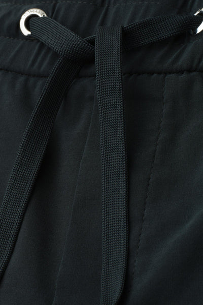 Dark green cotton shorts with drawstring waist and silver grommets, close-up front view