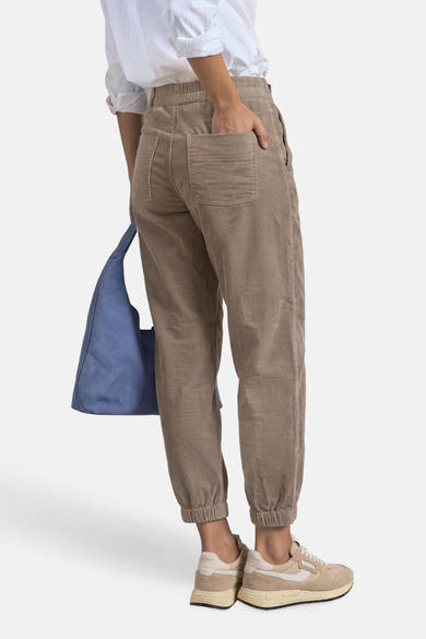 Vue arrière d’un chino beige STREET ONE porté avec une chemise blanche et des baskets, avec un sac bleu.