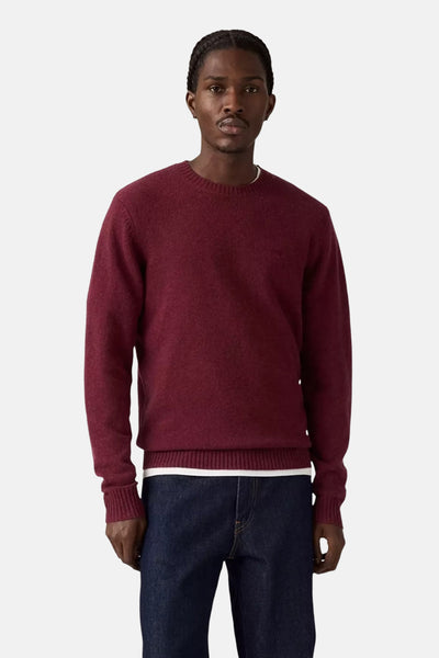 Bordeaux ronde hals trui van Levi's®, gedragen met een donkerblauwe jeans en een wit T-shirt.