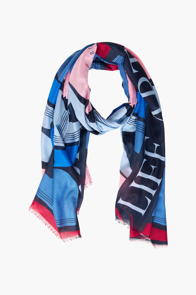 Blue foulard with bold geometric pattern and fringed edges, featuring pink, red, and navy accents in a looped display.