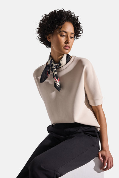 Zwarte sjaal van Street One, abstract patroon, gedragen om de nek met een beige top en een zwarte broek.