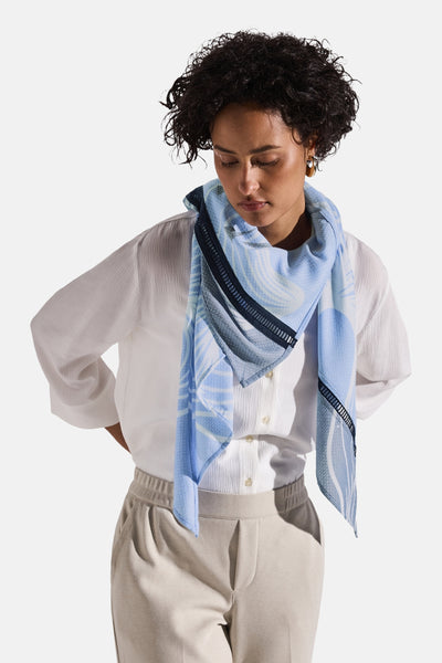 Foulard bleu de Street One avec motif géométrique abstrait porté avec une chemise blanche et un pantalon beige.