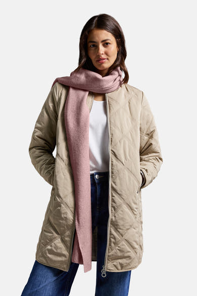 Roze sjaal van STREET ONE, gedragen met een beige gewatteerd jack, een wit T-shirt en een blauwe jeans.