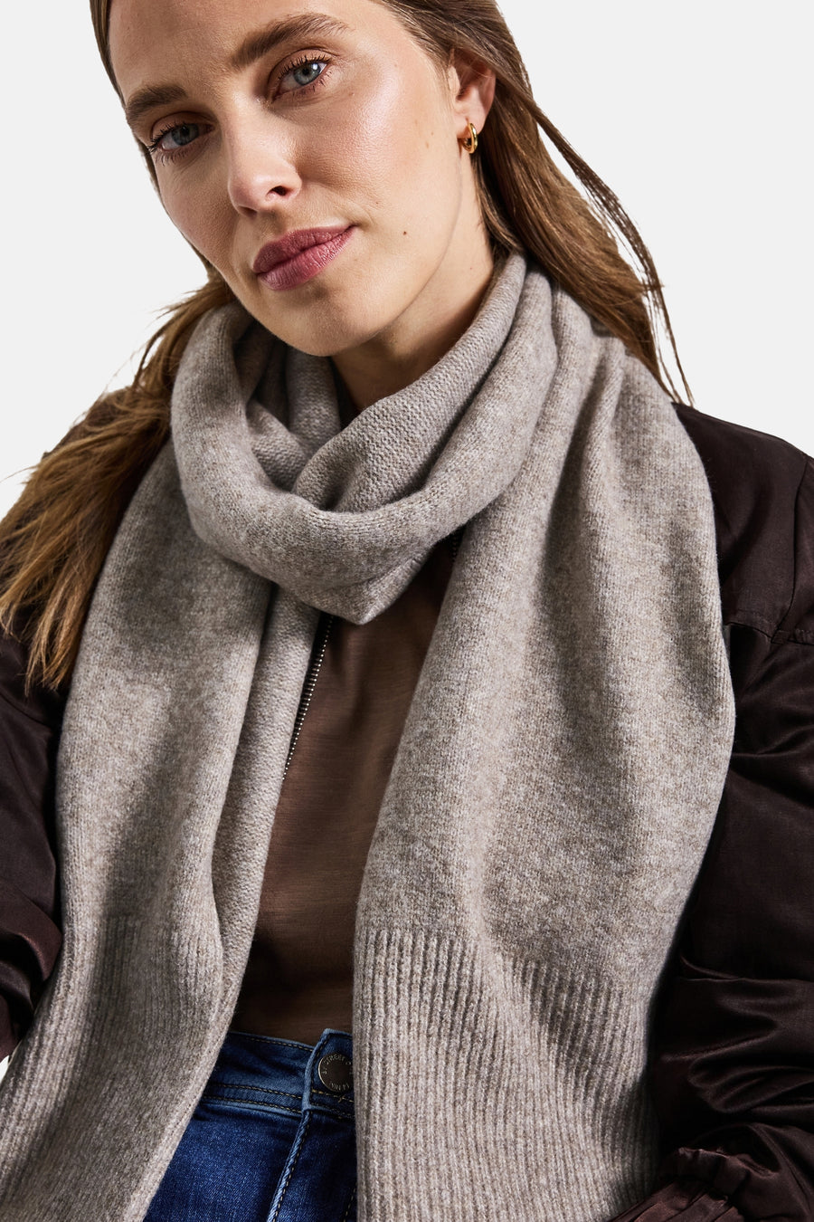 Beige gemêleerde gebreide sjaal van Street One, gedragen om de nek met een bruin jasje en een blauwe jeans.