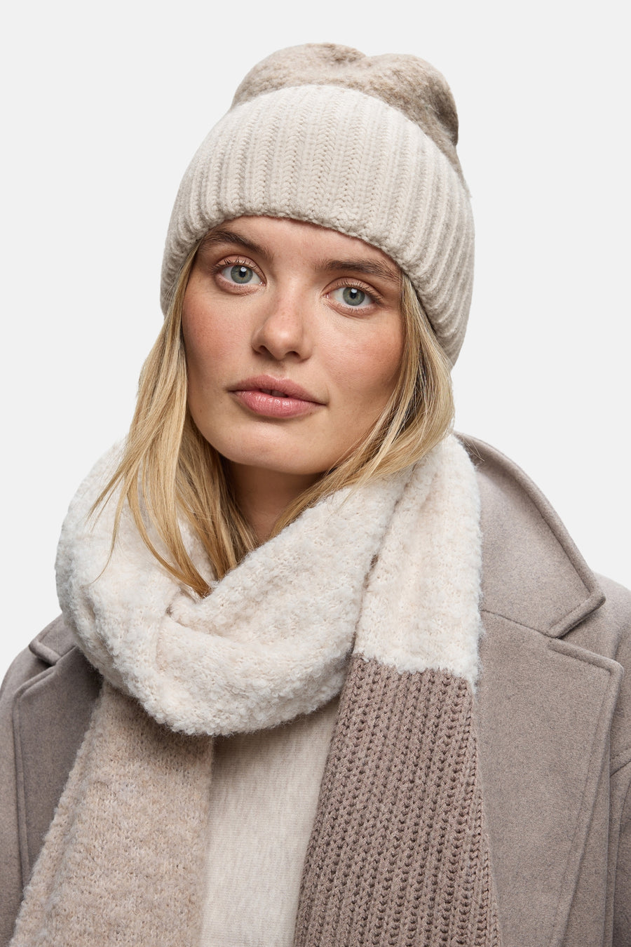 Ecru muts van Street One met gebreide textuur, gedragen met een imitatiebont sjaal en een beige jas.