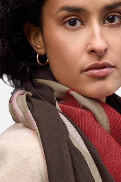 Foulard multicolore de Street One, à motifs et rayures, porté avec un manteau beige et des boucles d'oreilles dorées.
