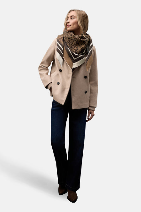 Écharpe cognac par Street One, avec motif imprimé et bords à rayures, portée avec un manteau beige et un jean foncé.