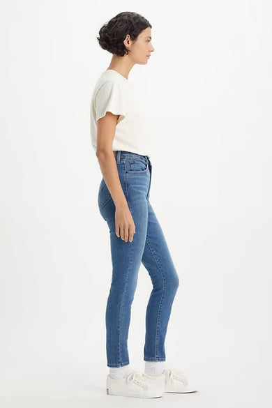 Jean skinny bleu moyen de Levi's, porté avec un t-shirt blanc et des chaussures de sport blanches.