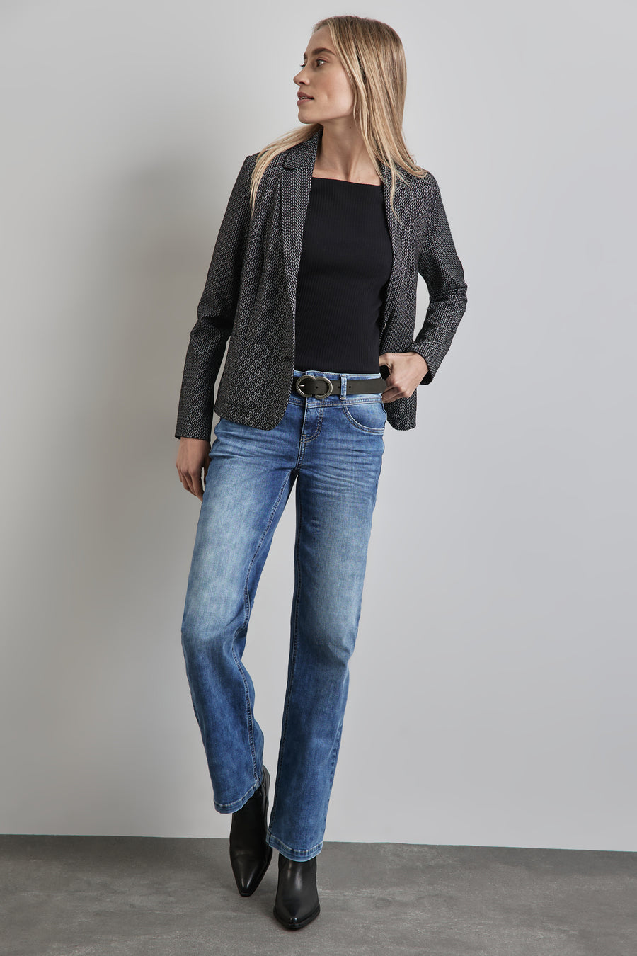 Ceinture noire par Street One, portée avec une veste à motif et un jean délavé.