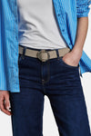 Beige riem van Street One met ronde gesp, gedragen met een donkerblauwe jeans en een blauw gestreept overhemd.