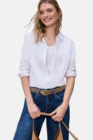 Ceinture cognac de STREET ONE portée avec un jean bleu et une chemise blanche, tenant un sac en daim marron.
