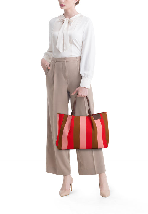 Sac à bandoulière multicolore de STREET ONE, rayures verticales, porté avec un chemisier blanc et un pantalon beige.
