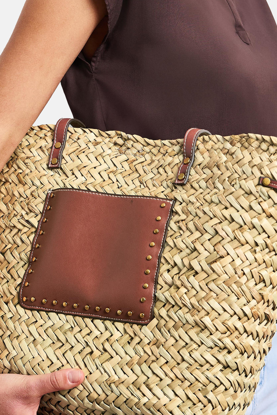 Sac à bandoulière beige de STREET ONE en paille tressée avec poche et poignées en cuir marron cloutées, tenu.