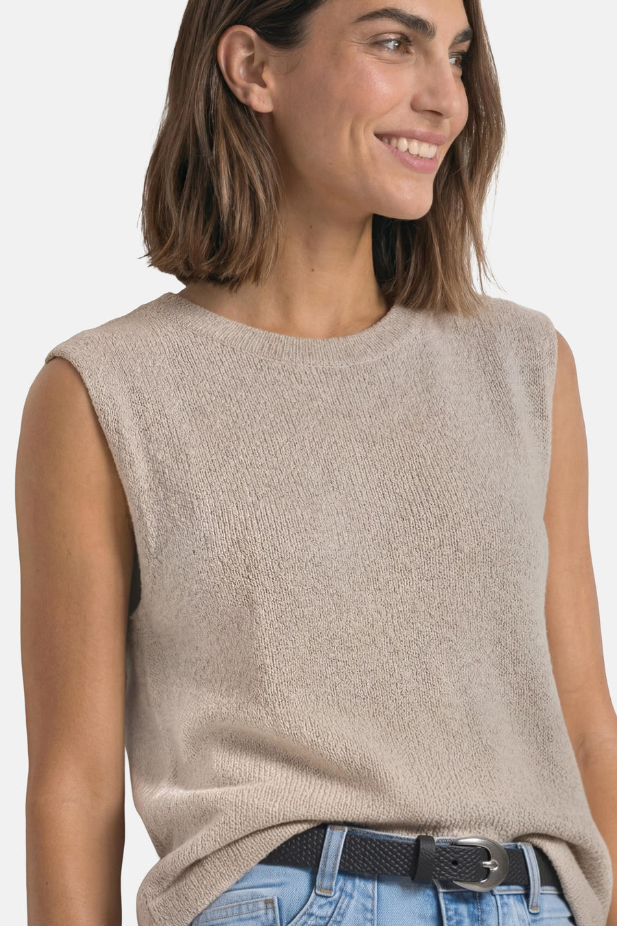 Black textured belt with silver buckle by STREET ONE, worn with light blue jeans and beige knit top, side view close-up.