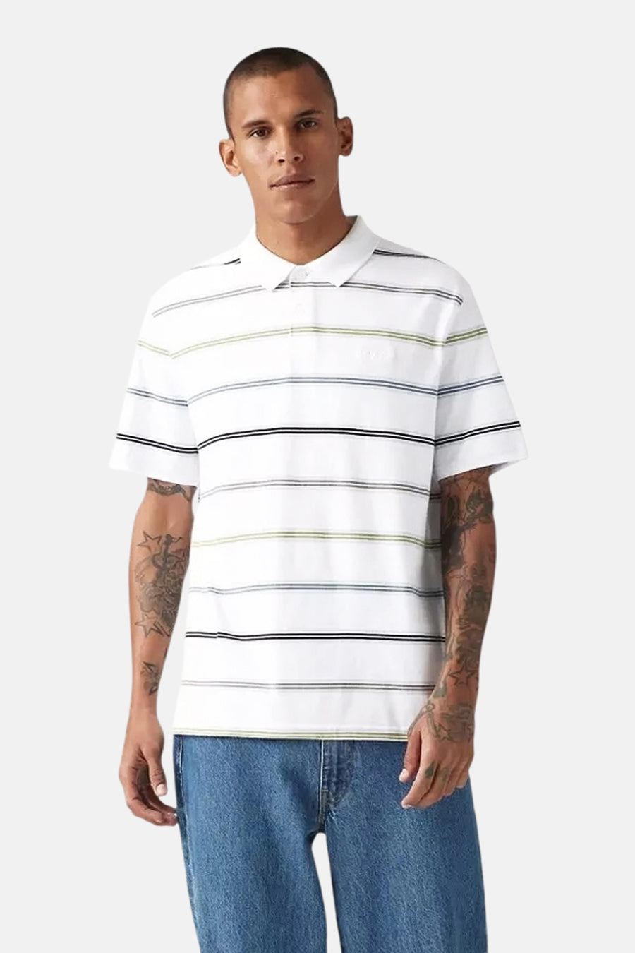 Wit gestreept poloshirt van Levi's®, gedragen met een blauwe spijkerbroek en met tatoeages op de armen.