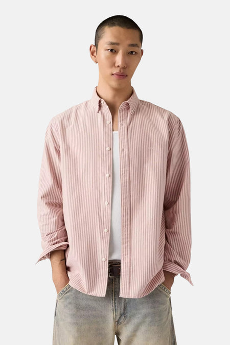 Chemise rose à rayures fines, manches longues retroussées, par Levi's®, portée sur un tee blanc, vue de face.