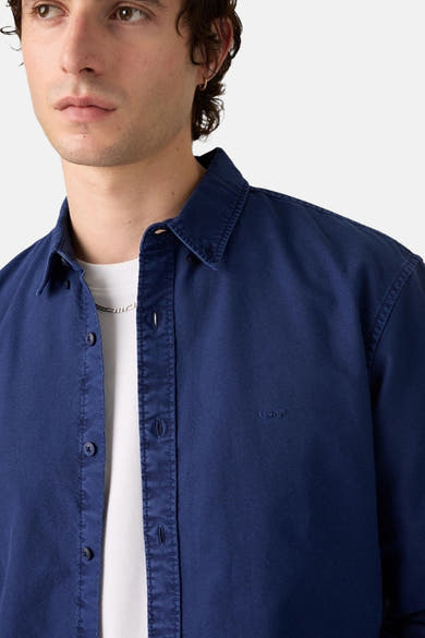 Navy blue long-sleeve shirt by Levi's with classic collar, button-down front, and chest logo, worn over white tee, close-up front view