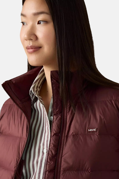 Korte bordeauxrode jas van Levi's, gedragen over een gestreept overhemd, close-up.