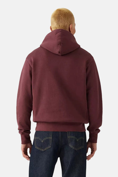 Sweat à capuche bordeaux de Levi's®, vue de dos, porté avec un jean bleu foncé.
