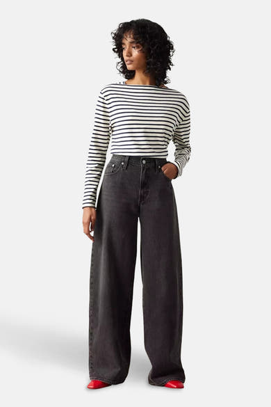 Rechte zwarte denim jeans van Levi's®, gedragen met een gestreept topje en rode schoenen.