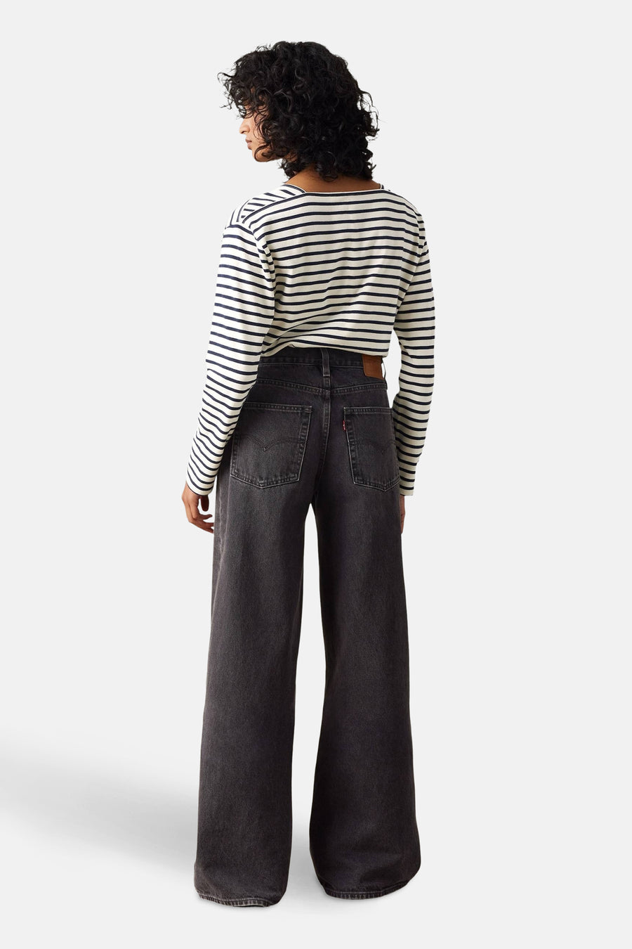 Rechte zwarte spijkerbroek van Levi's®, met zichtbare zakken en stiksels, gedragen met een gestreept T-shirt.