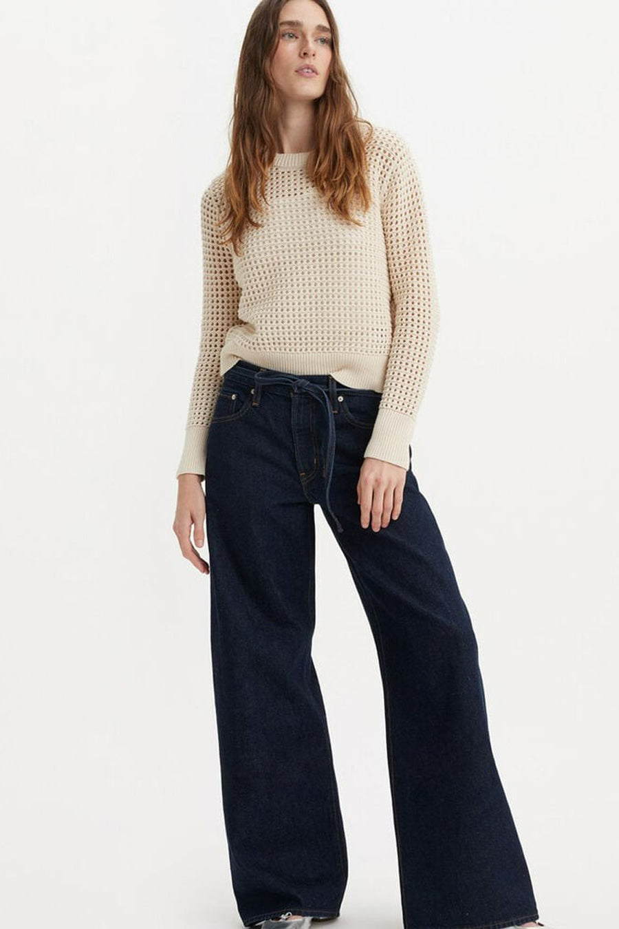 Rechte donkerblauwe spijkerbroek van Levi's®, gedragen met een beige kabeltrui.