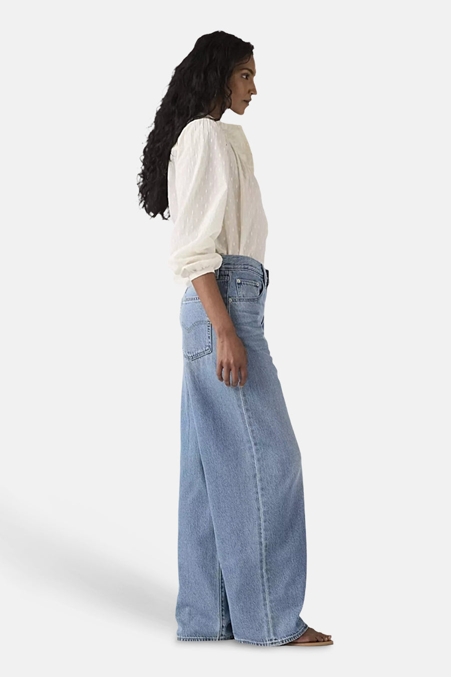 Rechte middellange blauwe spijkerbroek van Levi's®, wijde pijpen met een taps toelopende zoom, gedragen met een witte, getextureerde blouse.