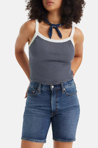Korte spijkerbroek van Levi's®, klassieke pasvorm middellichtblauw, gedragen met een gestreept hemdje en zwarte sandalen.