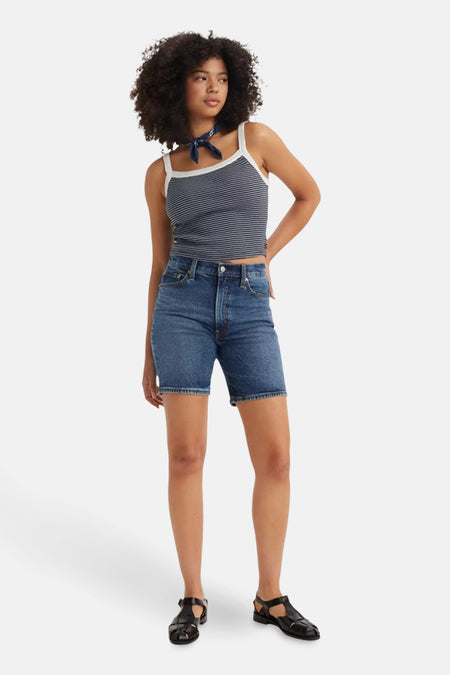 Korte spijkerbroek in blauw van Levi's, gedragen met een gestreept topje en zwarte sandalen