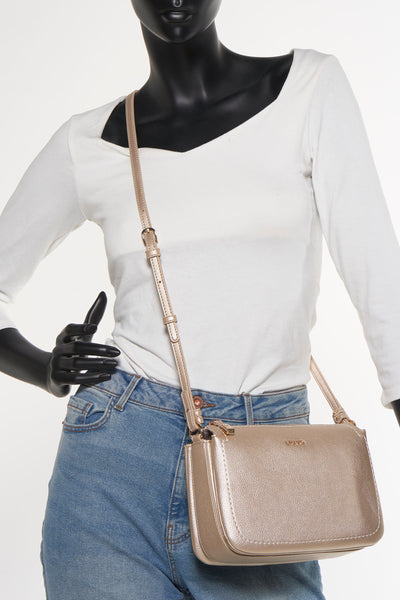 Sac bandoulière doré par LIU JO, porté sur un mannequin avec un jean bleu et un t-shirt blanc à manches longues.