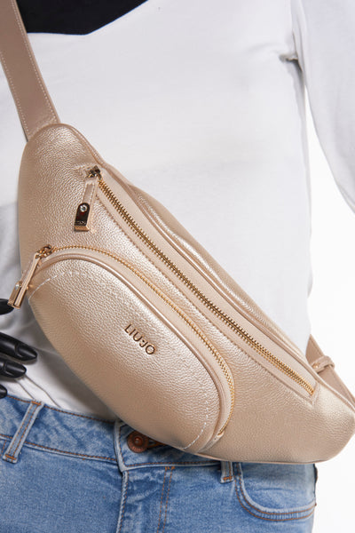 Gouden schoudertas van LIU JO, gedragen over een witte top en een blauwe jeans.