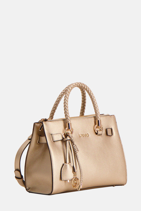 Sac à main doré de LIU JO avec anses tressées et breloque décorative, sur fond uni.
