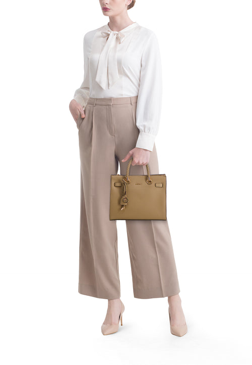 Groene handtas van LIU JO, in de hand gedragen door een vrouw met een beige blouse en broek.