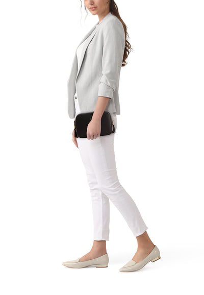 Sac à bandoulière noir de LIU JO, porté avec un blazer gris et un pantalon blanc.